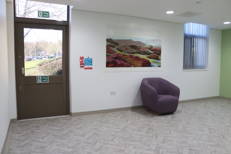 Entrance room with door and chair under artwork