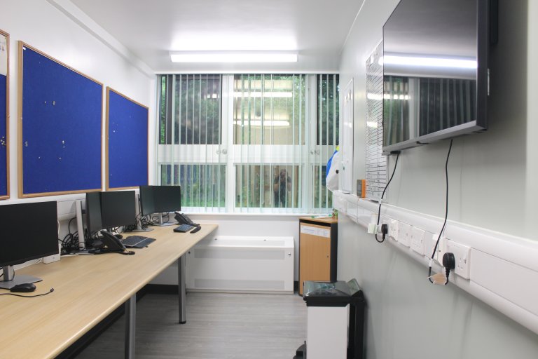 Staff area with a desk, computers and large monitor